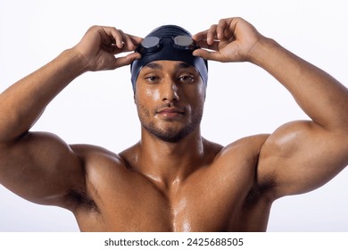 A young biracial male swimmer adjusts his swimming goggles. His confident expression and athletic build suggest he is a professional swimmer. - Powered by Shutterstock