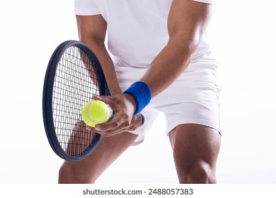 A young biracial man prepares to serve in a tennis match on a white background. He's focused on the game, showcasing his athletic skill and concentration. - Powered by Shutterstock