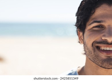 Young biracial man smiles brightly at the beach, with copy space. His relaxed demeanor suggests a carefree day by the seaside, unaltered. - Powered by Shutterstock