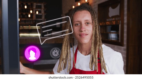 Young biracial man wearing red apron, holding a digital tablet in a cafe. Sporting light brown dreadlocks, smiling warmly with a red background - Powered by Shutterstock