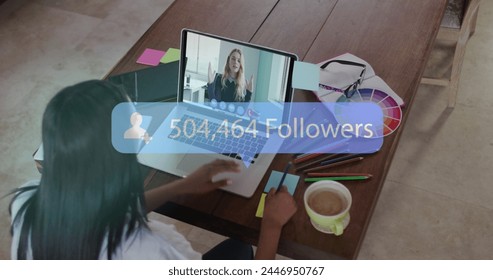 Young biracial woman engages in a video call on her laptop. She appears focused on growing her social media presence, as indicated by the follower count.