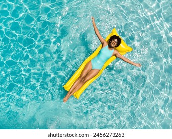 Young biracial woman enjoys a relaxing day at the pool, with copy space. She's lounging on a yellow float, radiating joy in the summer sun. - Powered by Shutterstock