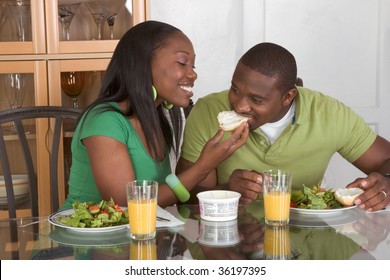 Young Black African American Couple Sitting By Glass Table And Eating Meal Of Salad, Bagels With Cream Cheese And Orange Juice