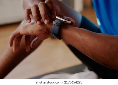 Young Black African American Male Checking His Data On His Smart Fitness Watch After Working Out At Home On His Yoga Mat