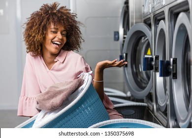 Young Black African American Woman Holding A Basket Of Clothes To Be Washed In A Automatic Laundry