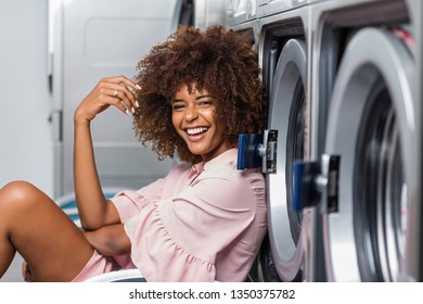 Young black African American woman waiting her clothes to be washed in a automatic laundry - Powered by Shutterstock