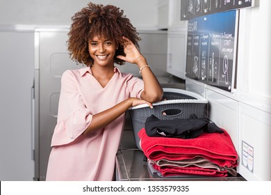 Young Black African American Woman Washing Her Clothes In A Automatic Laundry -Transalted Text : Dry, Empty Your Pocket,  Fill The Machine, Pay At The Central, Select The Temperature, Press Start To B