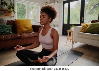 Young black african american woman with afro doing yoga at home in her living room - Powered by Shutterstock