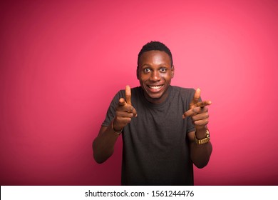 Young Black African Guy Standing  On A Pink Wall Looking Straight Into The Camera  Doing A Funny Face