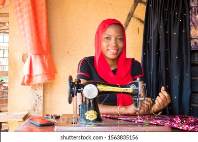 young black African woman sawing  using analog  sawing machine sitting in her small local shop 
