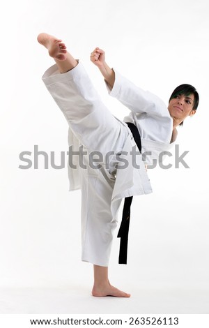 Young black belt karate fighter training hight kick . Isolated woman portrait on white background