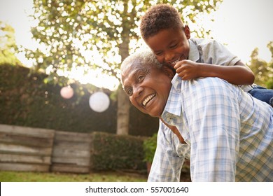 Young Black Boy Climbing On His GrandfatherÃ¢??s Back In Garden