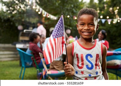 Young black boy holding flag at 4th July family garden party