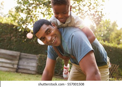 Young black boy playing on dadÃ¢??s back in a garden, low angle - Powered by Shutterstock