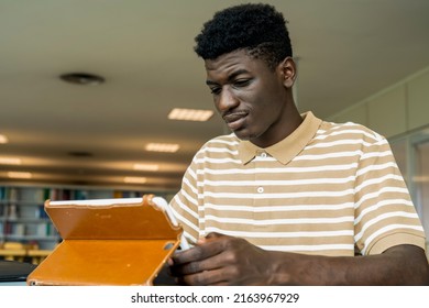 Young black boy using a tablet in a library