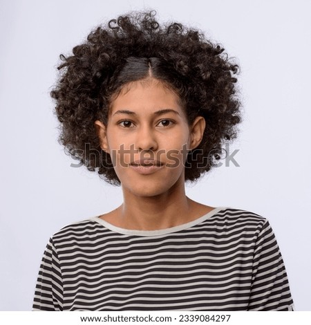 Young black Brazilian woman in close-up looking forward, wearing striped t-shirt and glasses, white background.