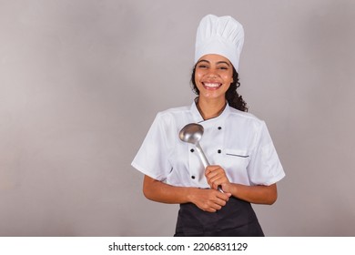 joven brasileña negra, cocinera. Sujetando una escalera de cocina para preparar caldos y sopas.