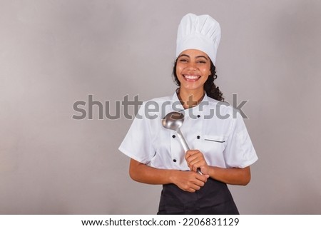 young black Brazilian woman, cook. Holding kitchen ladle for preparing broths and soups.