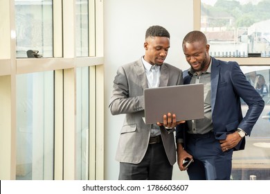 Young Black Business Men Standing Together Holding A Laptop, Discussing Business