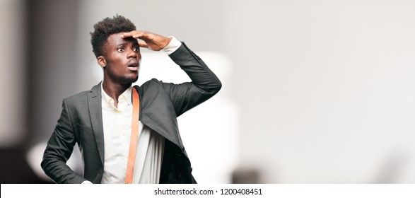 Young Black Businessman Looking Far Off Into The Distance, Searching For A Distant Object With A Confused Look.