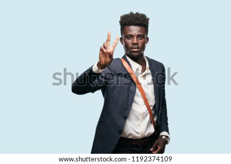 young black businessman with a proud, happy and confident expression; smiling and showing off success while gesturing victory, giving an "achiever" look, celebrating triumphantly.