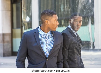 A young black businessman is standing by a mirror and looking at the reflection / Looking at Mirror  - Shutterstock ID 166180196