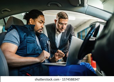 Young Black Car Mechanic Using Computer With His Manager In Auto Repair Shop. 