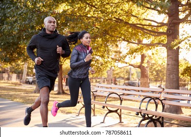 Young black couple jogging in a Brooklyn park, three quarter length