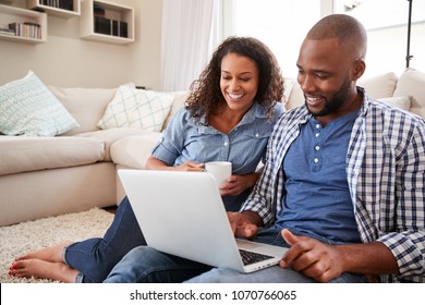 Young black couple using laptop sitting on the floor at home - Powered by Shutterstock