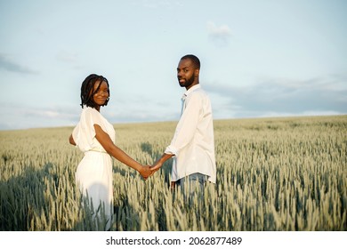 Young Black Couple Walking Through Green Field