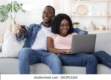 Young Black Couple Watching TV And Using Laptop, Weekend At Home