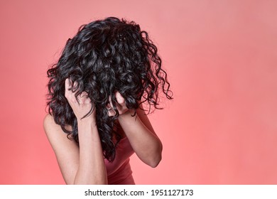 young black curly haired woman combing her hair following curly girl method on pink background. hair care concept. - Shutterstock ID 1951127173