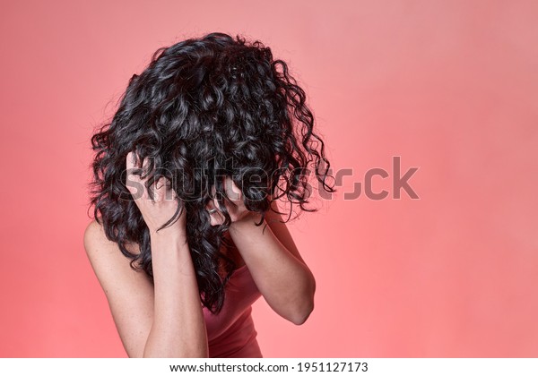 young black\
curly haired woman combing her hair following curly girl method on\
pink background. hair care\
concept.