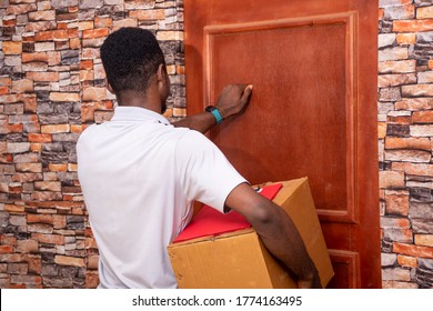 Young Black Delivery Company Worker Knocking On A Door