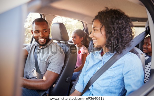 Young black\
family in a car on a road trip\
smiling
