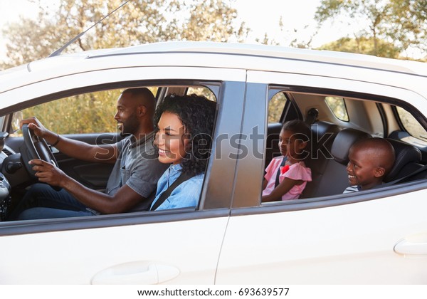 Young black\
family in a car smile on the road\
trip