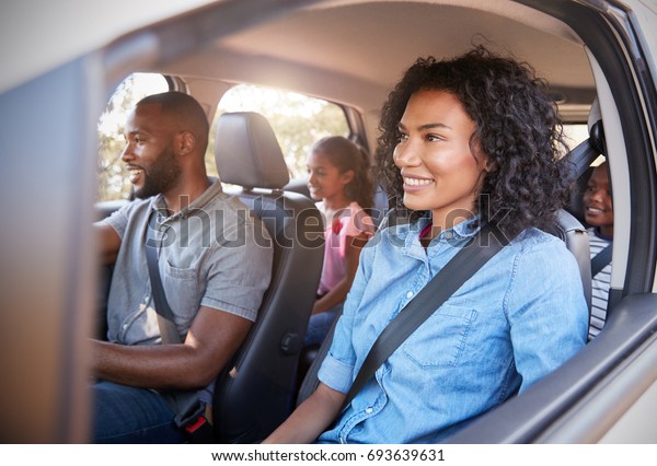 Young black family with children in a car going on\
road trip