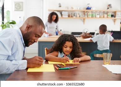 Young black family of four busy in their kitchen, close up