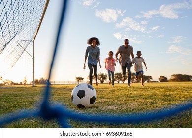 A Young Black Family Running After A Football During A Game