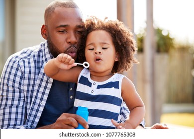 Young Black Father And Daughter Blowing Bubbles Outside