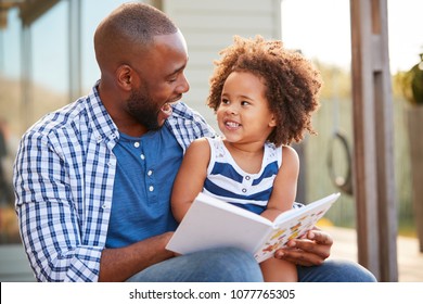 Young black father and daughter reading book outside - Shutterstock ID 1077765305