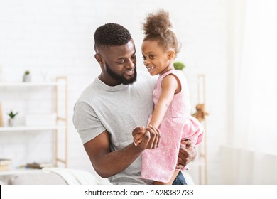 Young Black Father Holding Little Daughter Dressed In Beautiful Dress, Dancing Together At Home