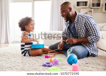 Young black father playing with daughter in the sitting room
