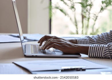 Young black female hands typing on pc keyboard. African business woman user using laptop computer working online, searching tech data in internet sitting at desk in home office. Close up view.