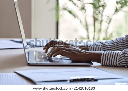 Young black female hands typing on pc keyboard. African business woman user using laptop computer working online, searching tech data in internet sitting at desk in home office. Close up view.