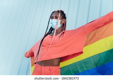 Young Black Gay Woman With Face Mask Holding A Lgbt Gay Pride Rainbow Flag - Focus On Girl's Face