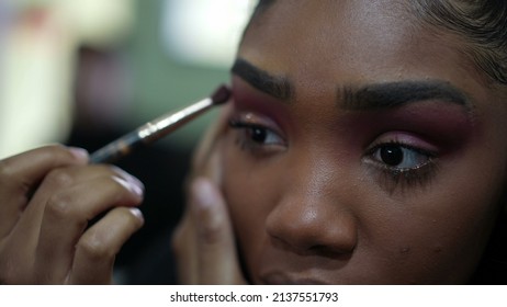 A Young Black Girl Applying Make-up In Front Of Mirror