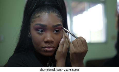 A Young Black Girl Applying Make-up In Front Of Mirror