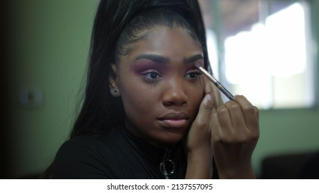 A Young Black Girl Applying Make-up In Front Of Mirror