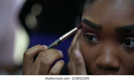 A Young Black Girl Applying Make-up In Front Of Mirror